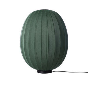 Oval, høj lampe i mørkegrøn med strikket overflade, sort base og synlig ledning.